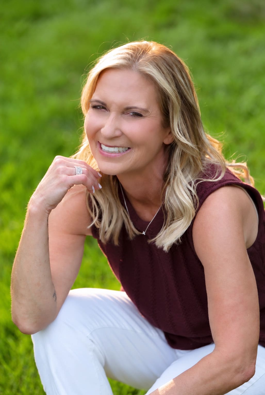 Donna Walker, smiling, seated in the grass on a summer evening